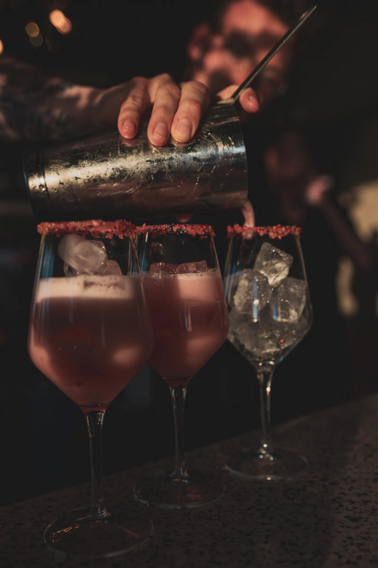 A bartender straining cocktails at Bar 66