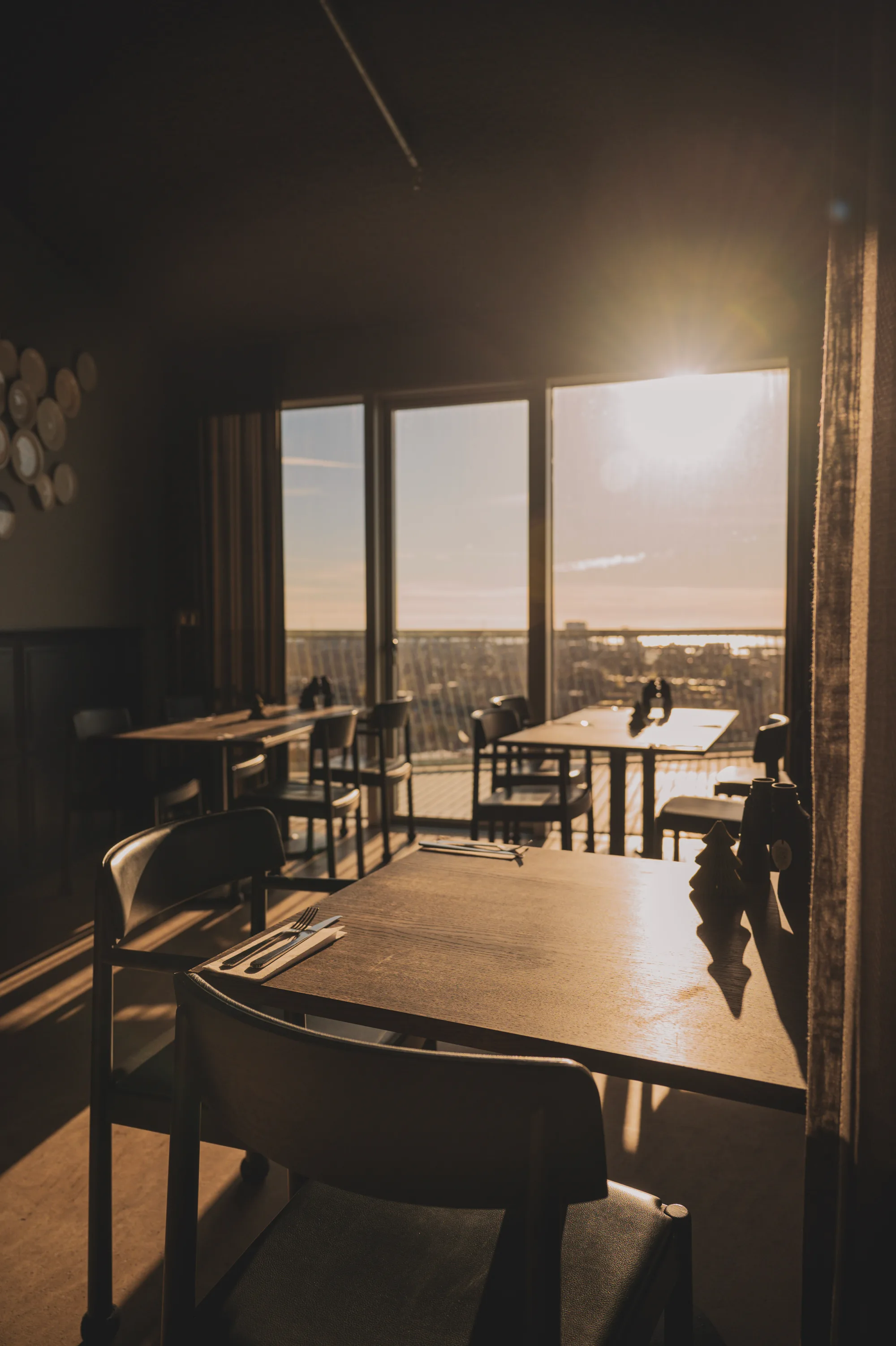 The dining room in late afternoon sun, tables laid along the windows